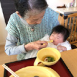 ひいおばあちゃんと一緒にお食い初めをしている写真